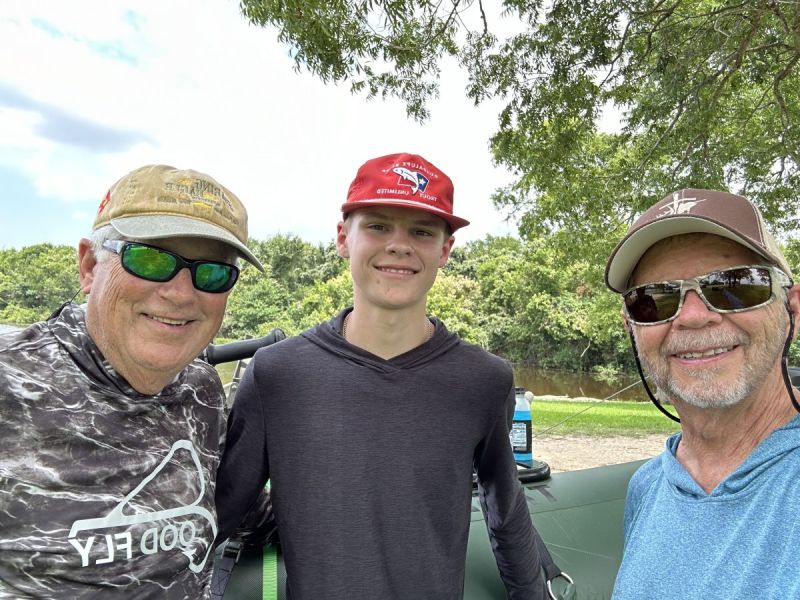 Three anglers of different generations smiling together on a lake outing
